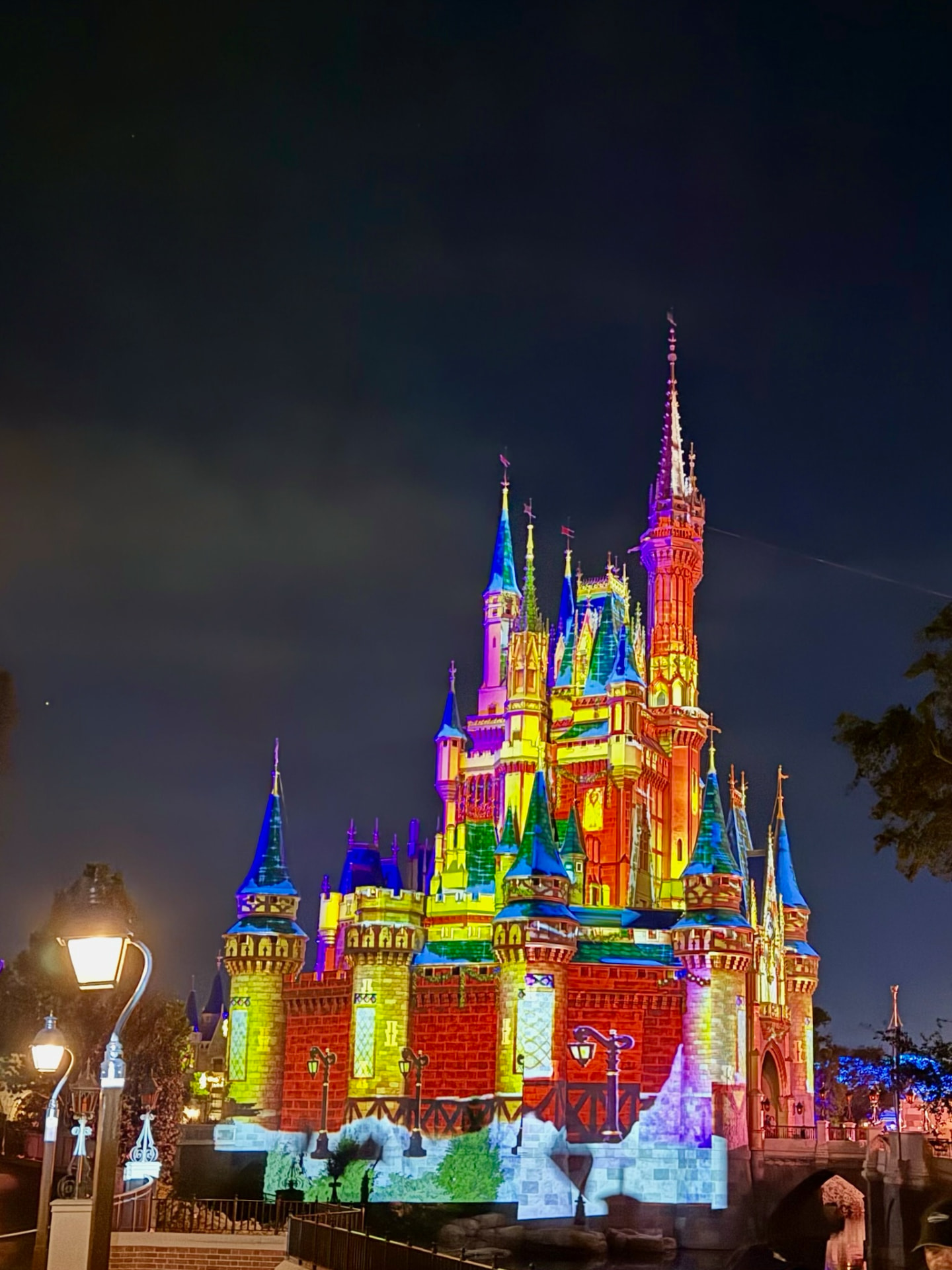 Cinderella Castle lit in rainbow colors at night
