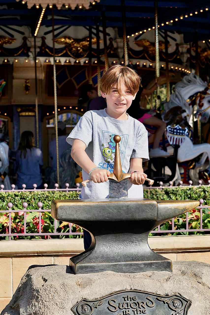 Boy pulling the Sword in the Stone at Magic Kingdom